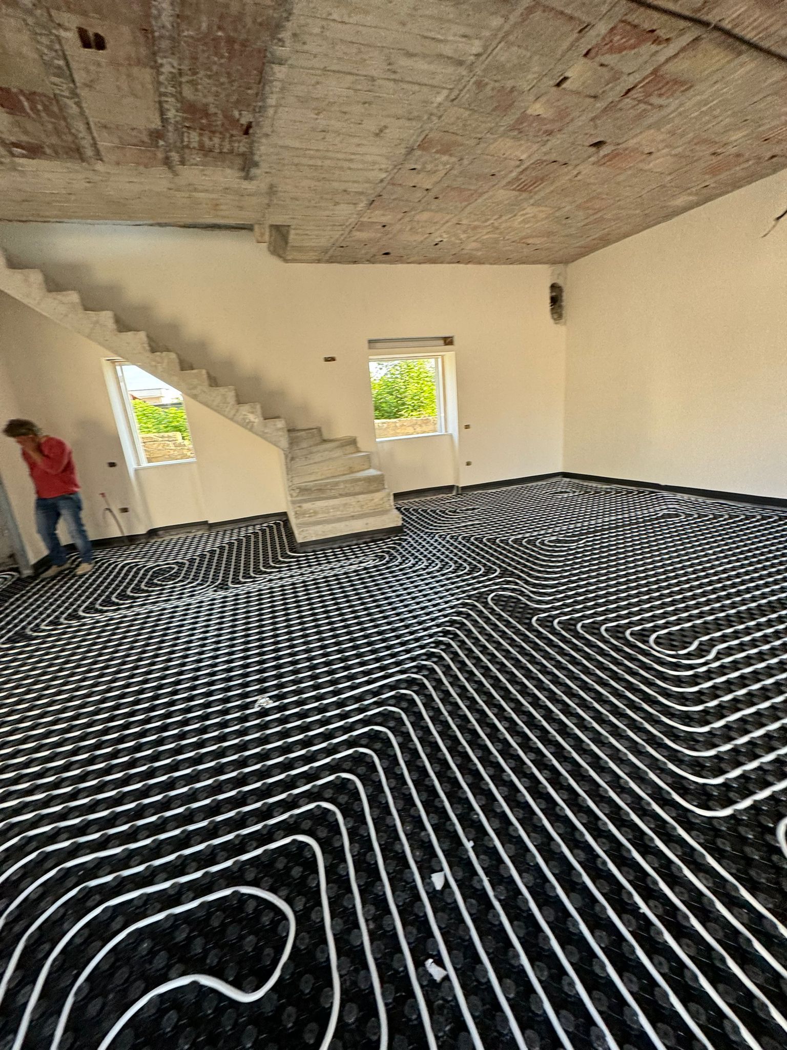 Un uomo è in piedi in una stanza con una scala sullo sfondo.