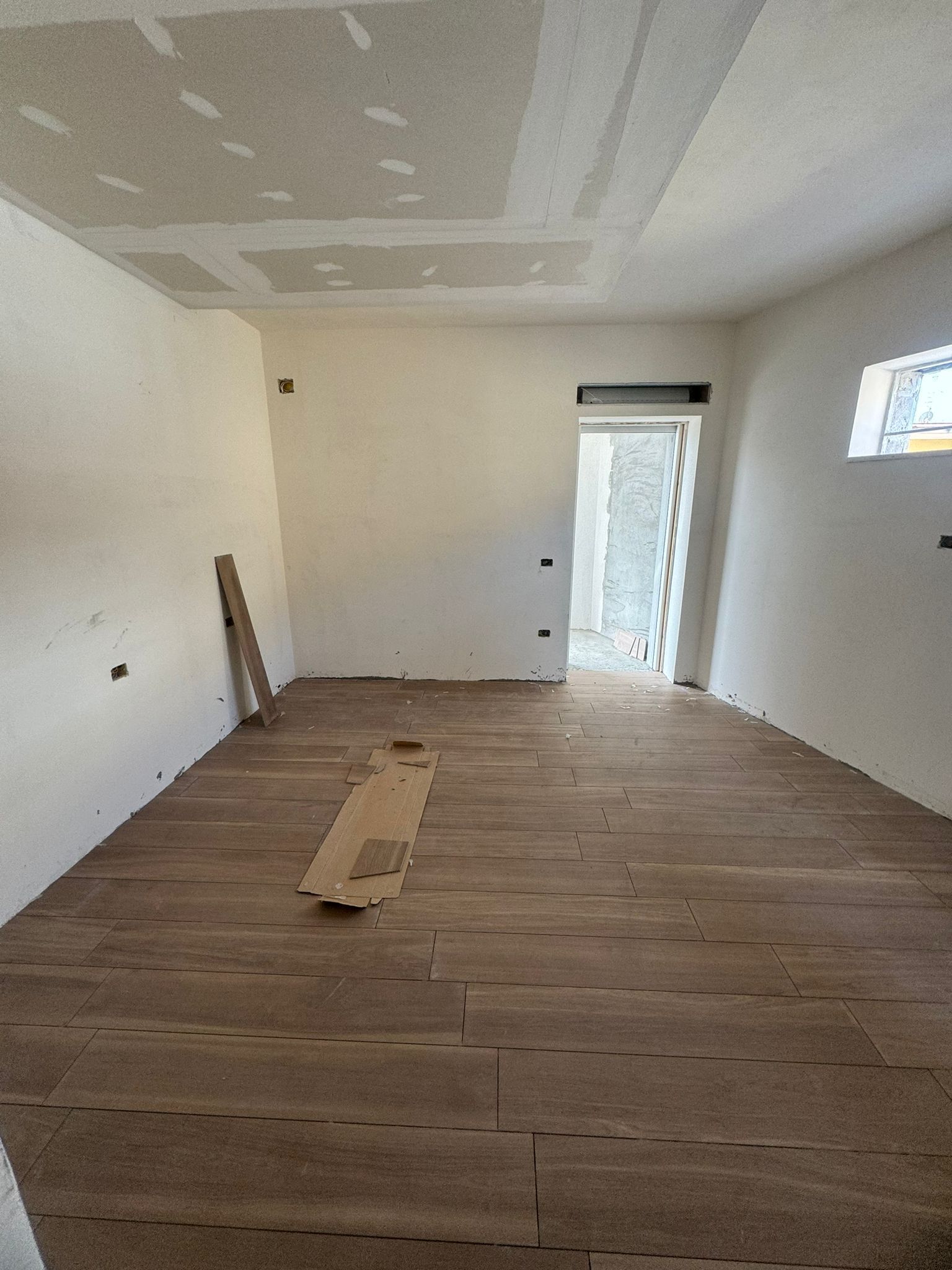 Una stanza con pavimento in legno e pareti bianche.