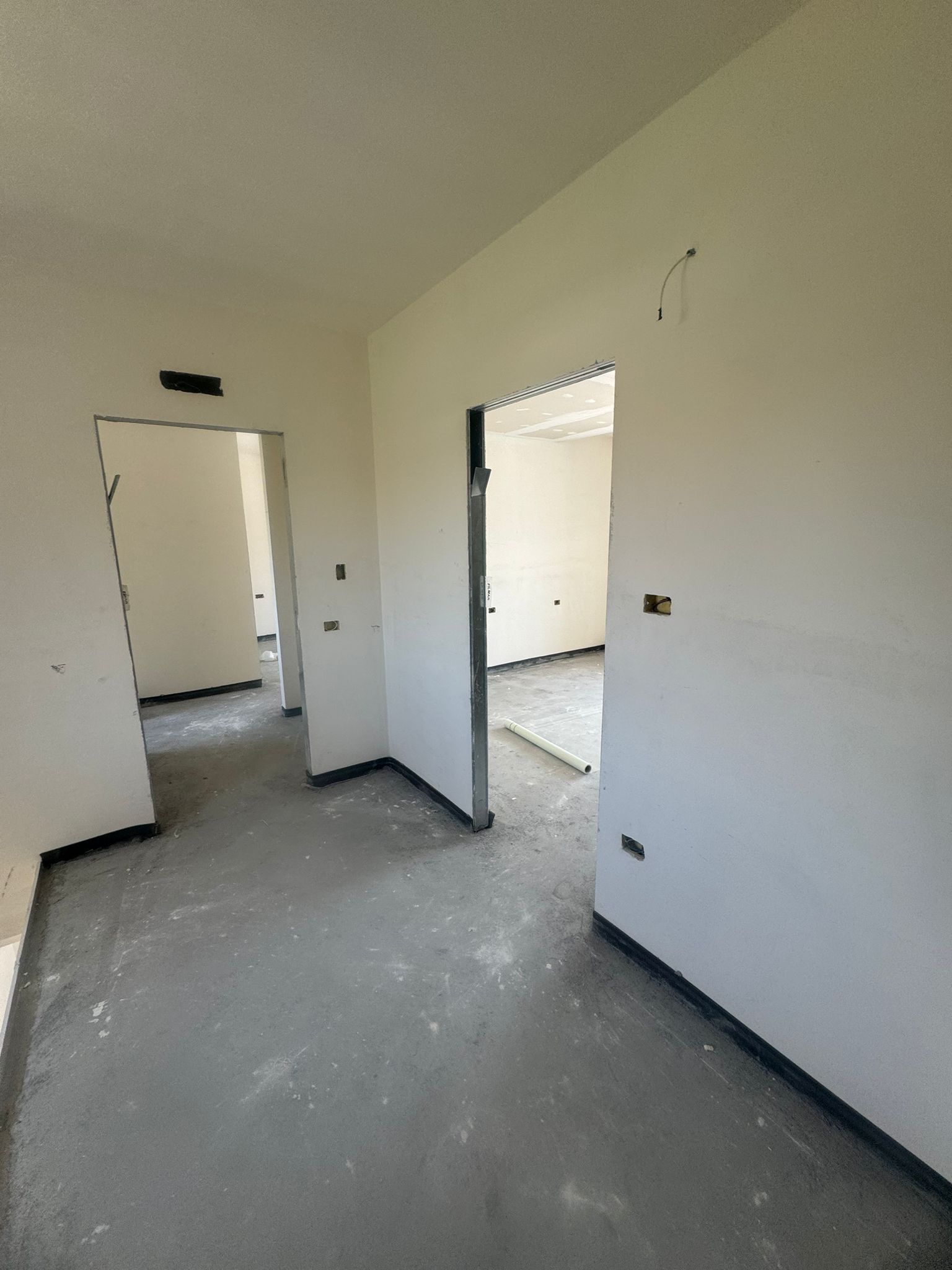 Una stanza vuota con pareti bianche e una porta che conduce a un'altra stanza.