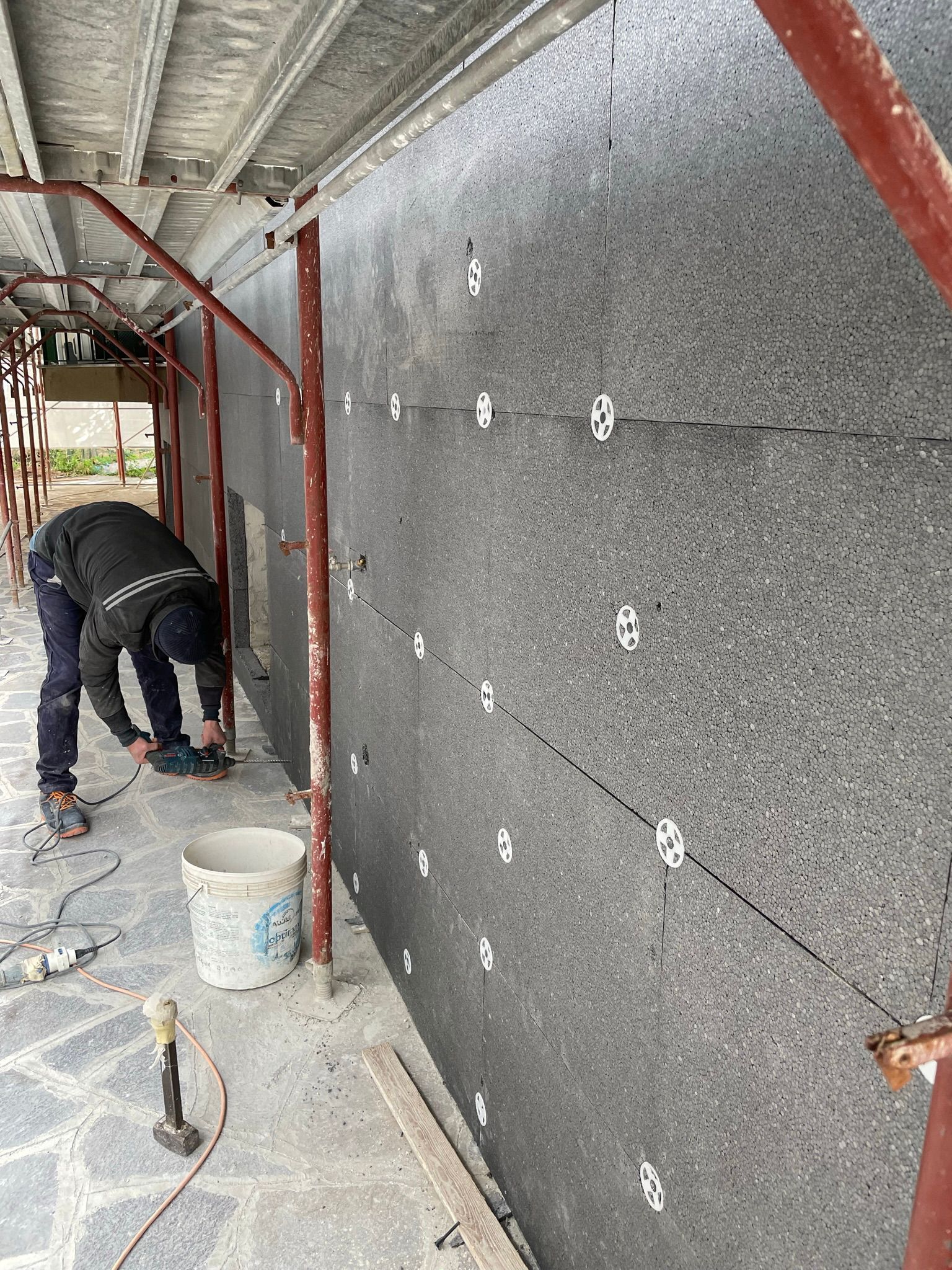 Un uomo sta lavorando su un muro sotto un'impalcatura.