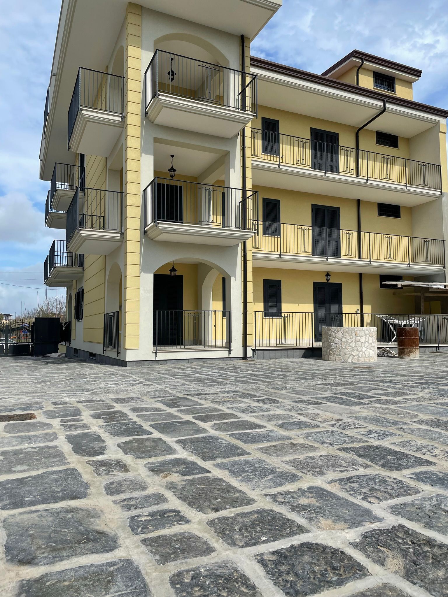 Un grande edificio giallo con balconi e un vialetto in mattoni di fronte