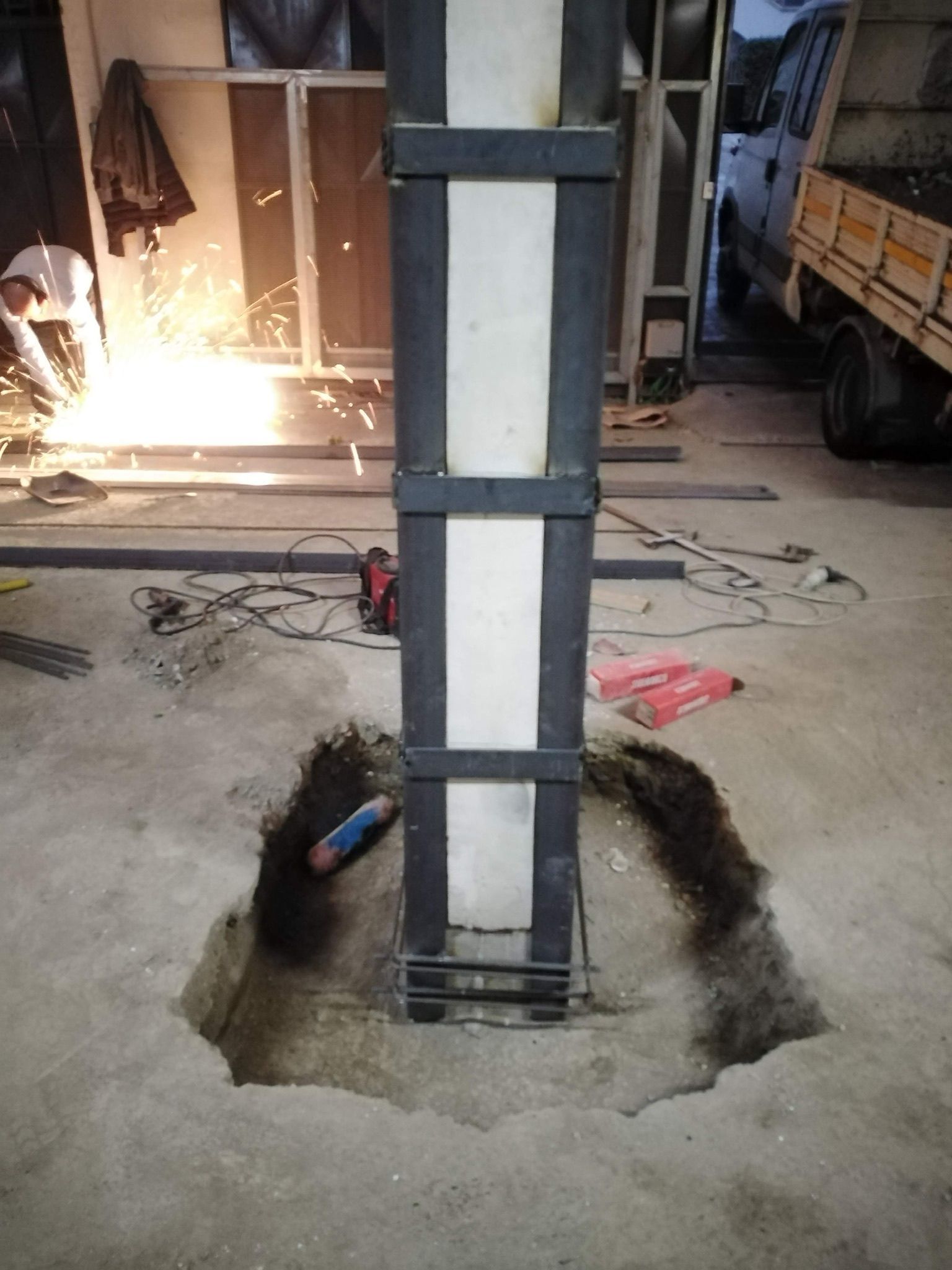 Un uomo sta saldando un palo di metallo in un garage.