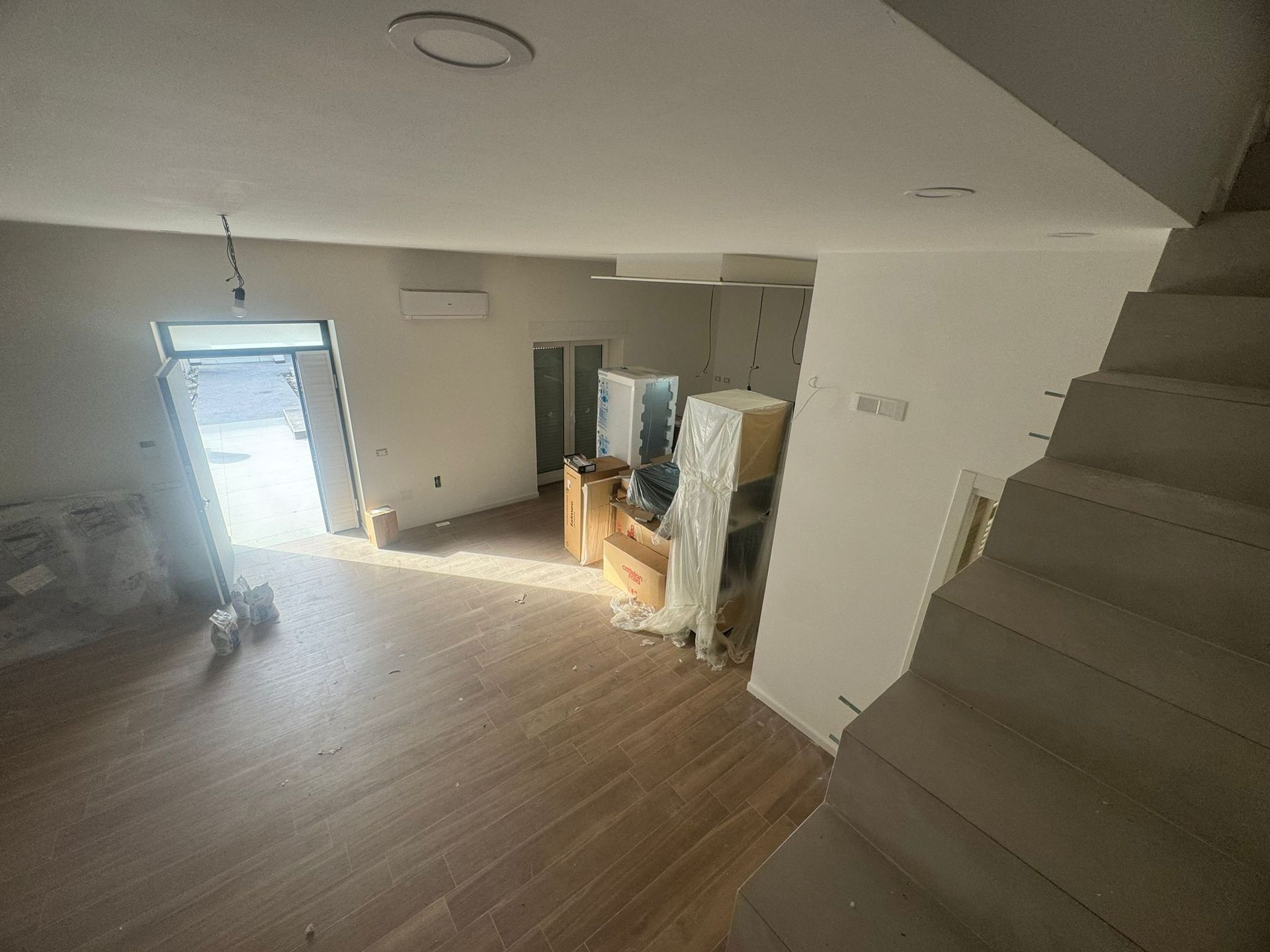 Una grande stanza vuota con pavimenti in legno e pareti bianche.