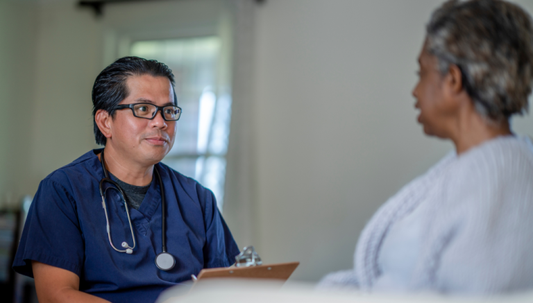 A doctor is talking to an elderly woman in a hospital bed.