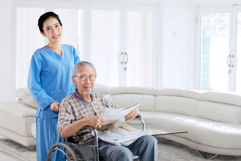 A nurse is standing next to an elderly man in a wheelchair.