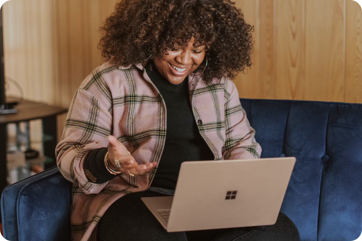 A woman is sitting on a couch using a laptop computer.