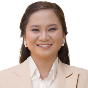 A woman wearing a tan jacket and white shirt smiles for the camera