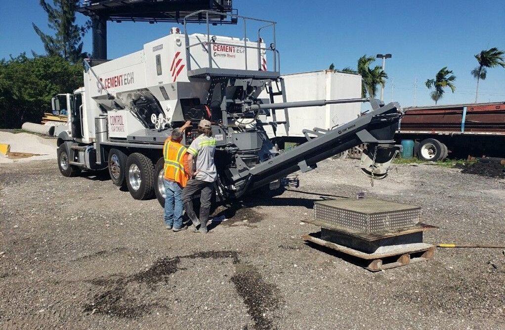 A group of construction workers are standing in front of a concrete mixer truck.
