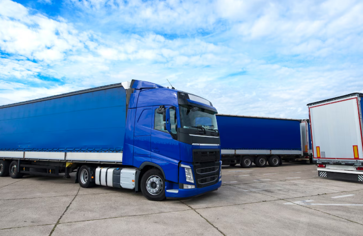 Un camion blu è parcheggiato accanto a un camion bianco in un parcheggio.
