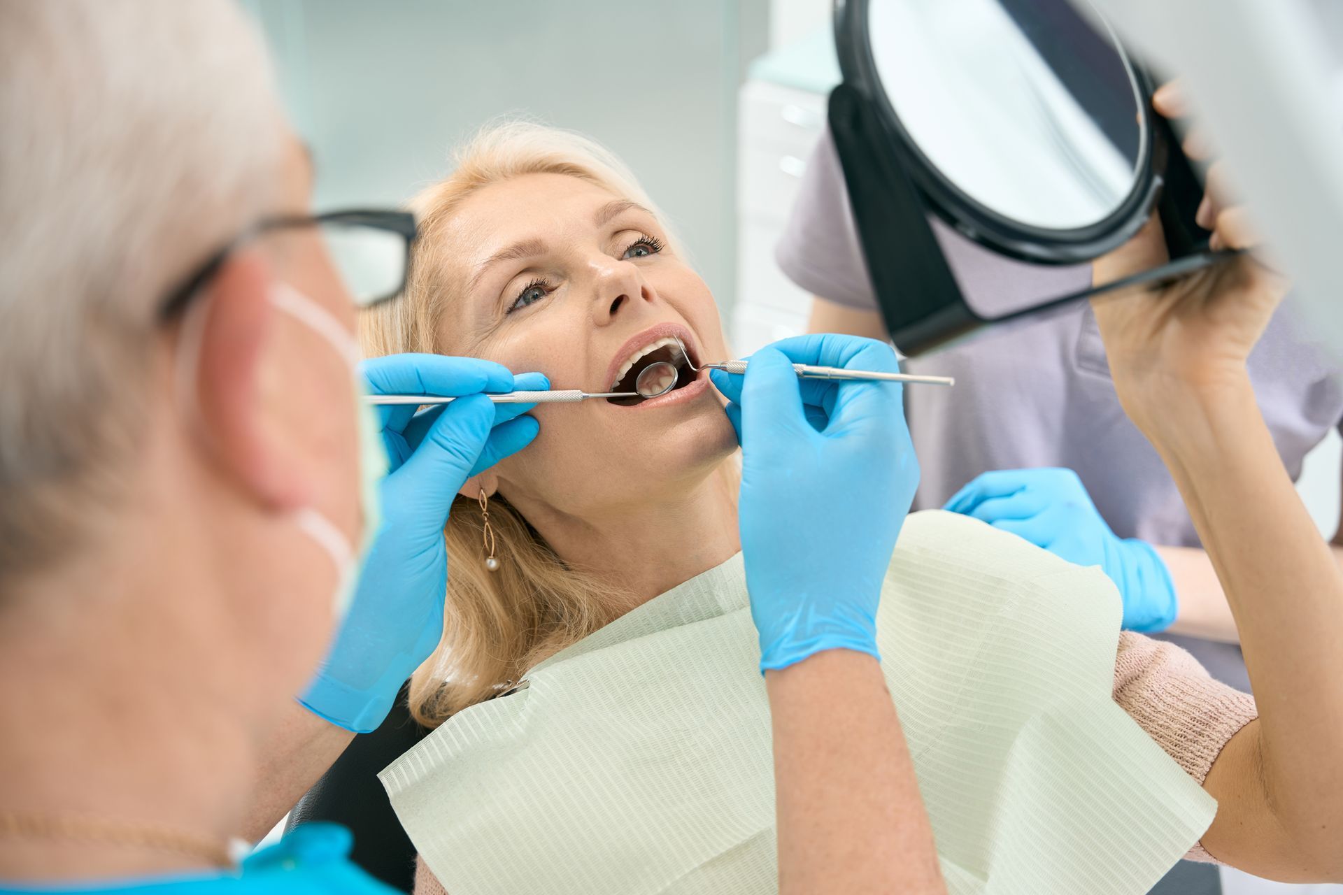 Woman getting teeth cleaned by dentist, essential for dental crowns and oral health.