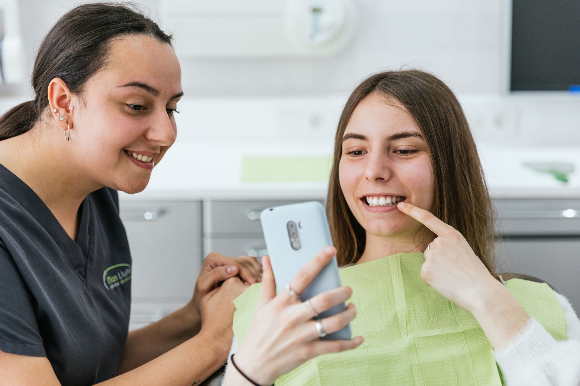 A dentist is showing a picture of the patient's new smile on a smartphone after the treatment.
