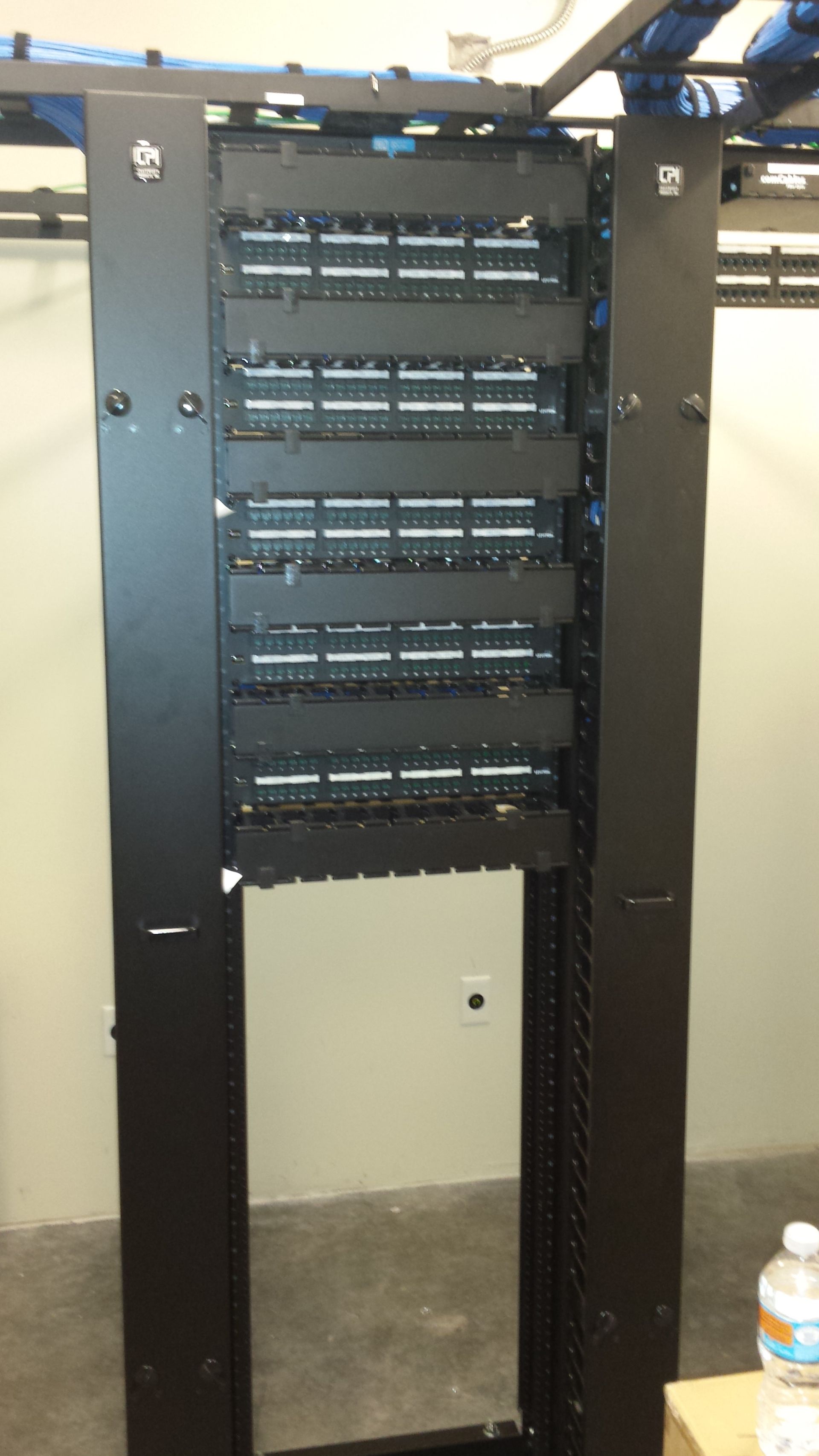 Black server rack with numerous horizontal shelves, empty, in an indoor setting.