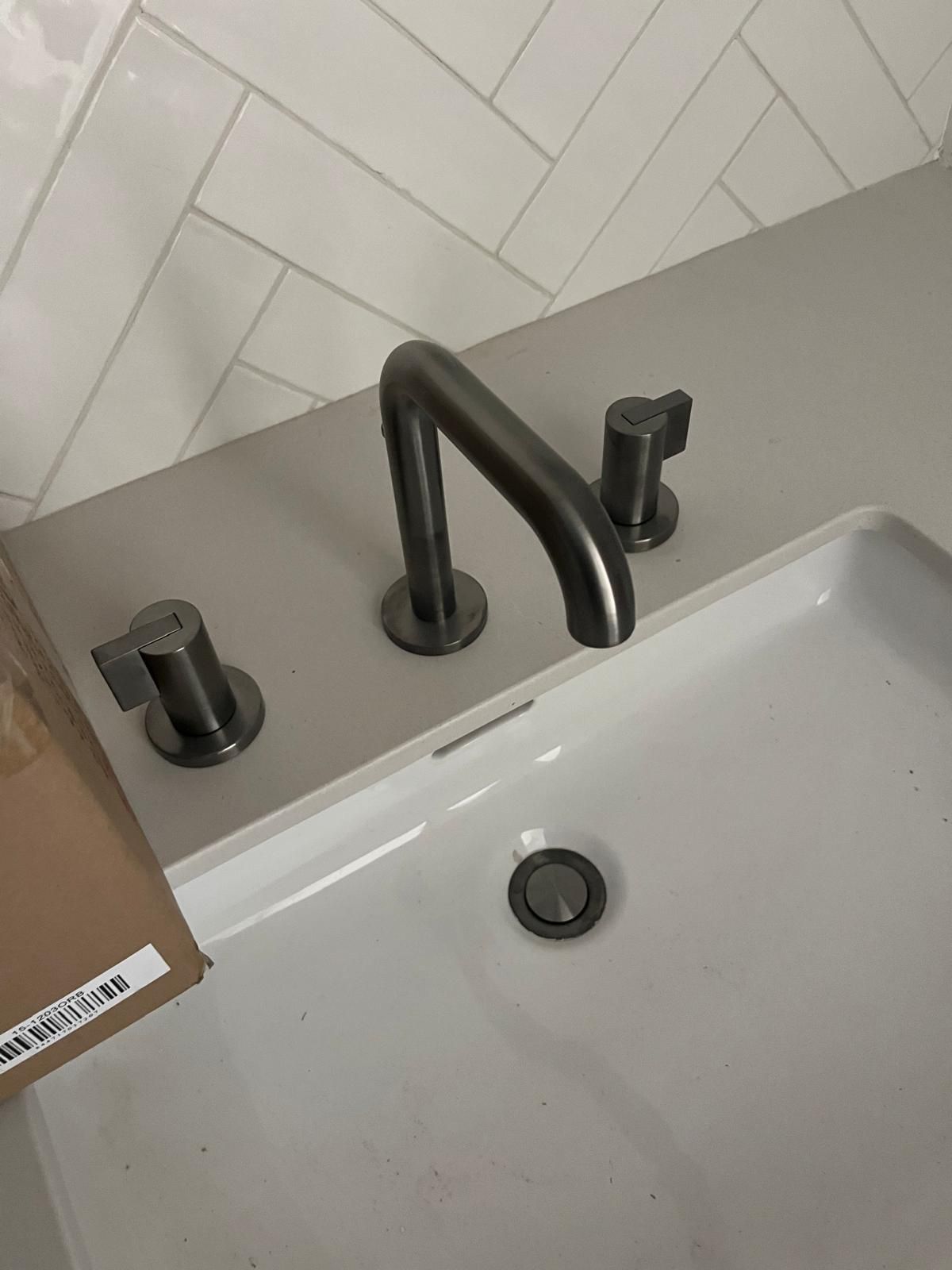 Bathroom sink with brushed nickel faucet, two handles, and white basin, against a light gray countertop.