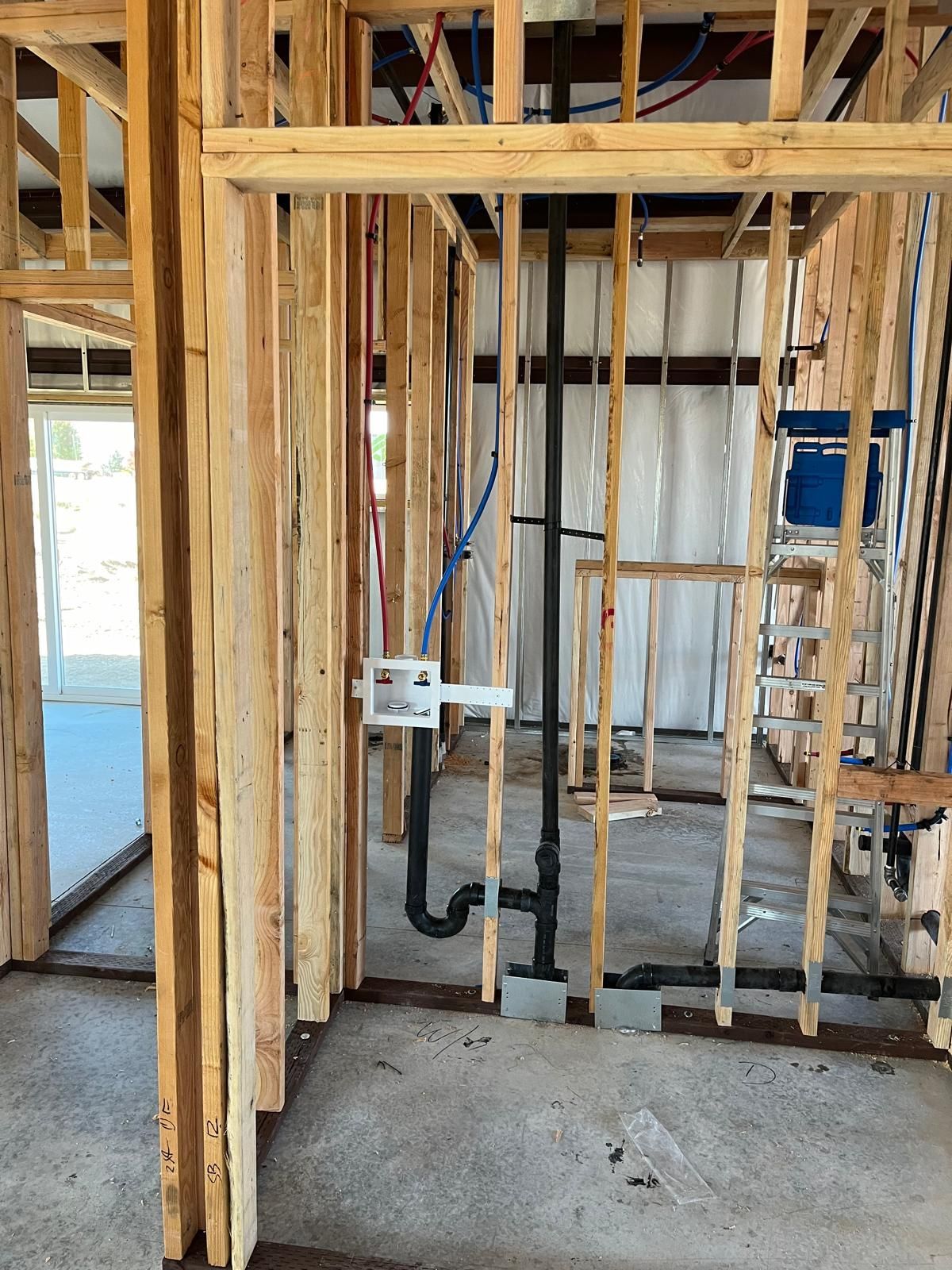 Interior framing with plumbing and electrical work visible in a construction site.