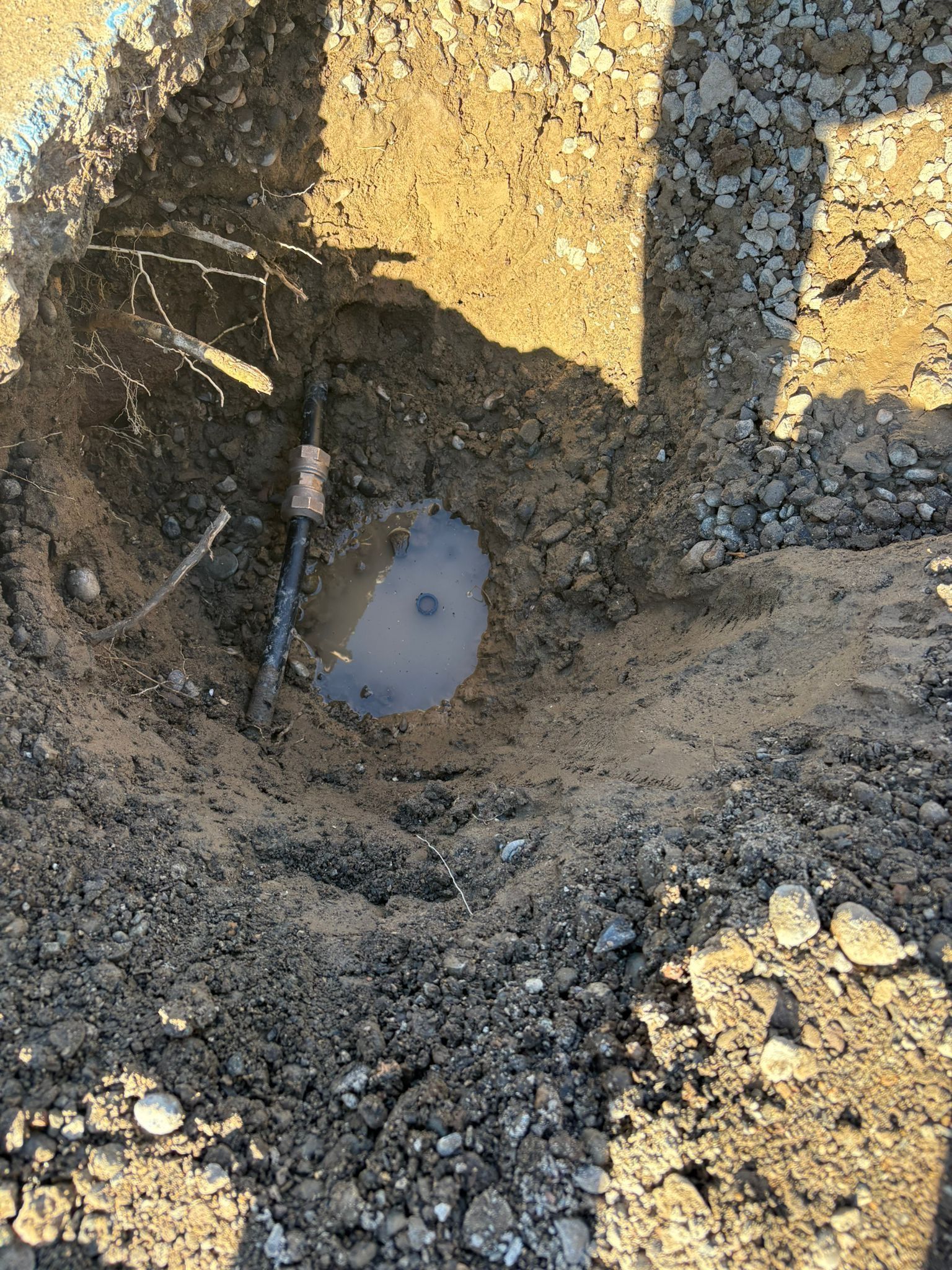 Hole in ground with water valve, plumbing, and soil.
