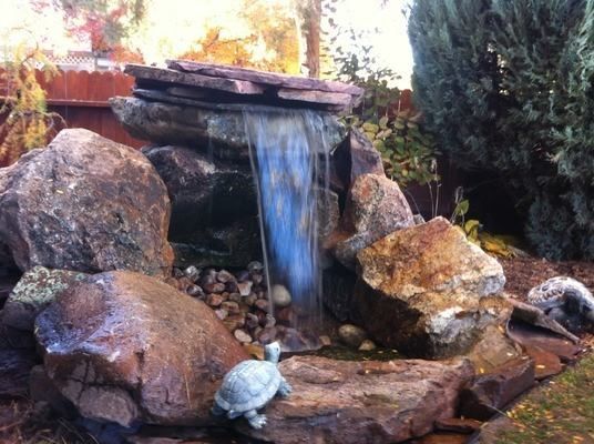 A tiered stone waterfall feature with a small decorative turtle figure at the base of the pool.