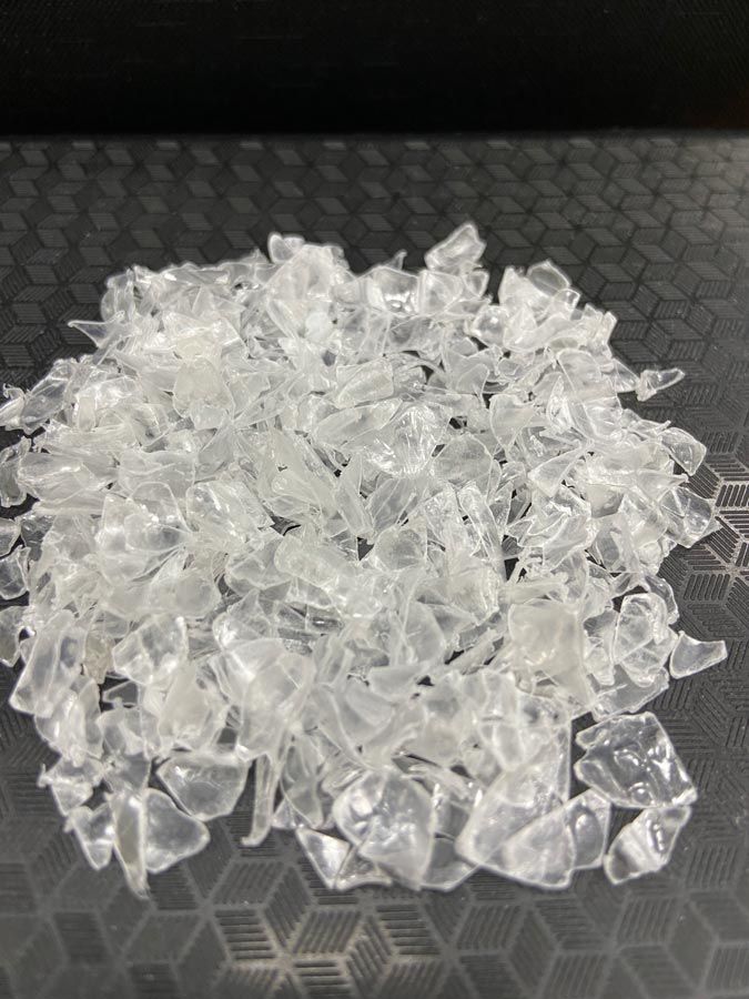 A pile of clear plastic chips on a black surface.