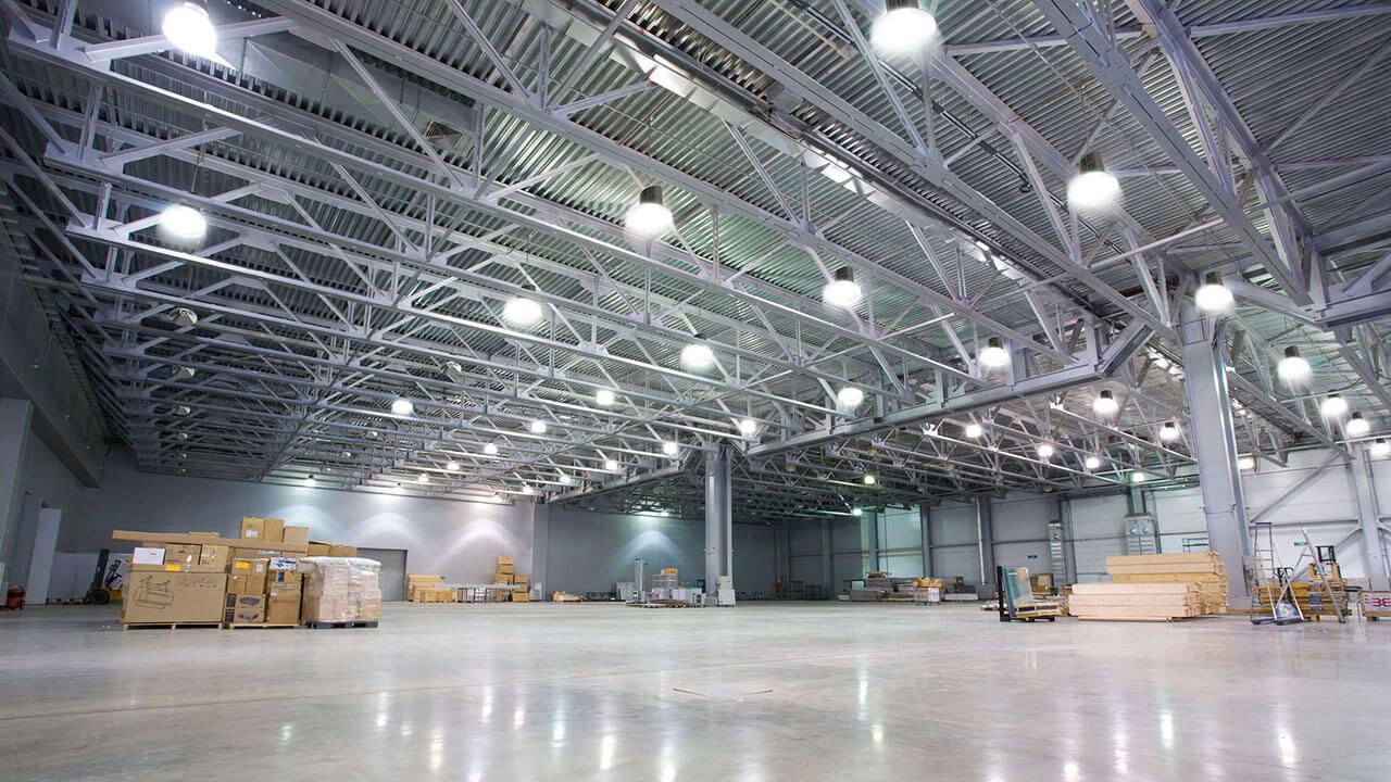 A large empty warehouse with lots of lights on the ceiling.