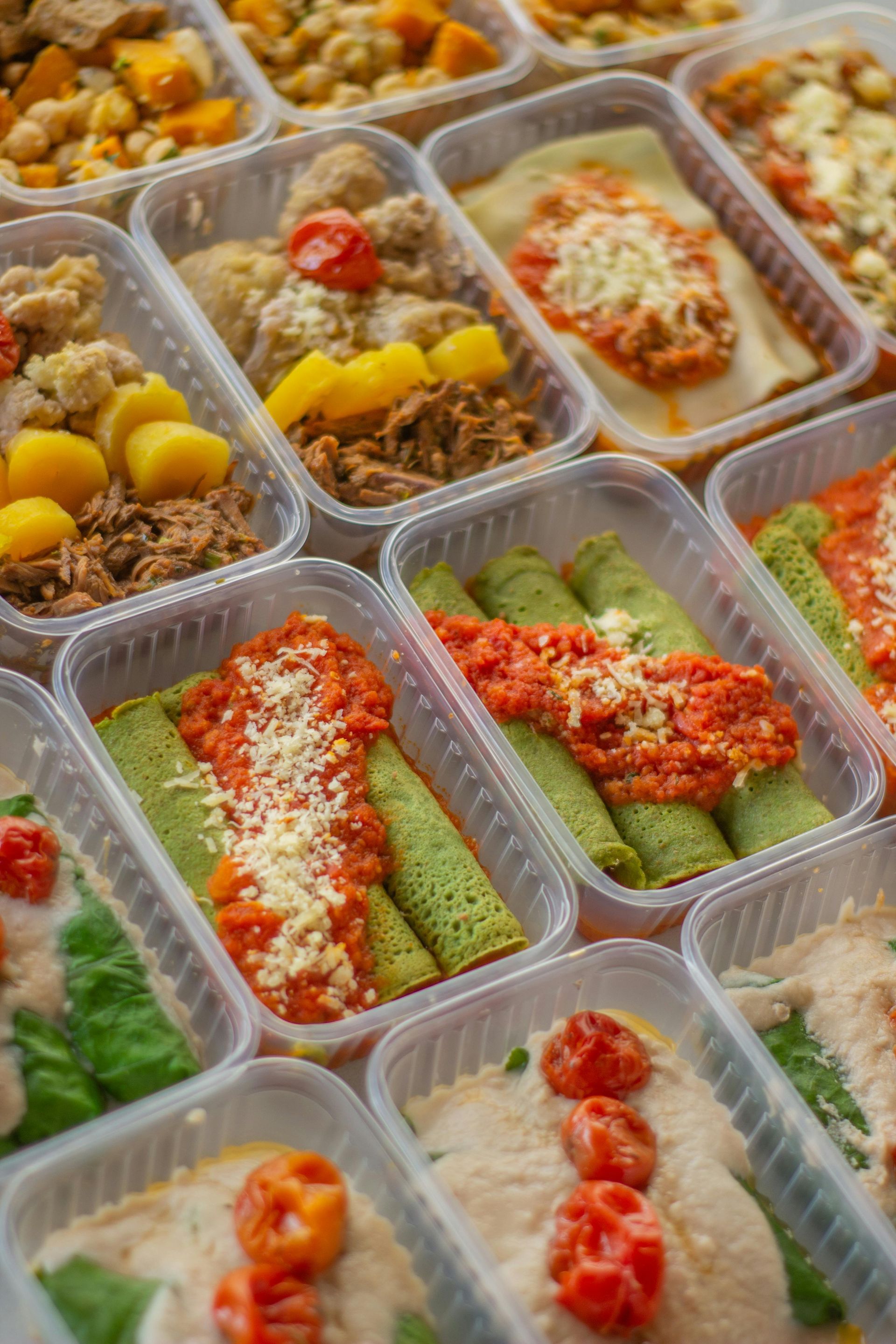 Prepared meals in plastic containers: lasagna, crepes, and other dishes.