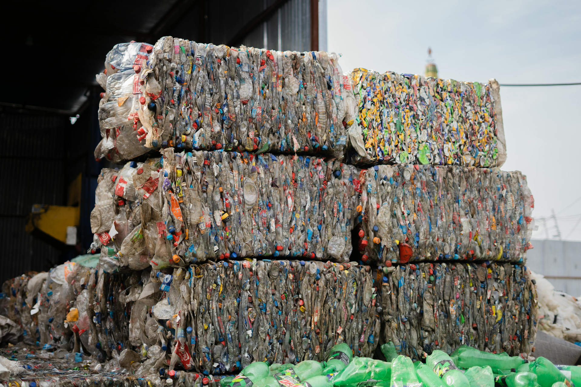Stacked rectangular bales of compressed plastic bottles in a recycling facility.