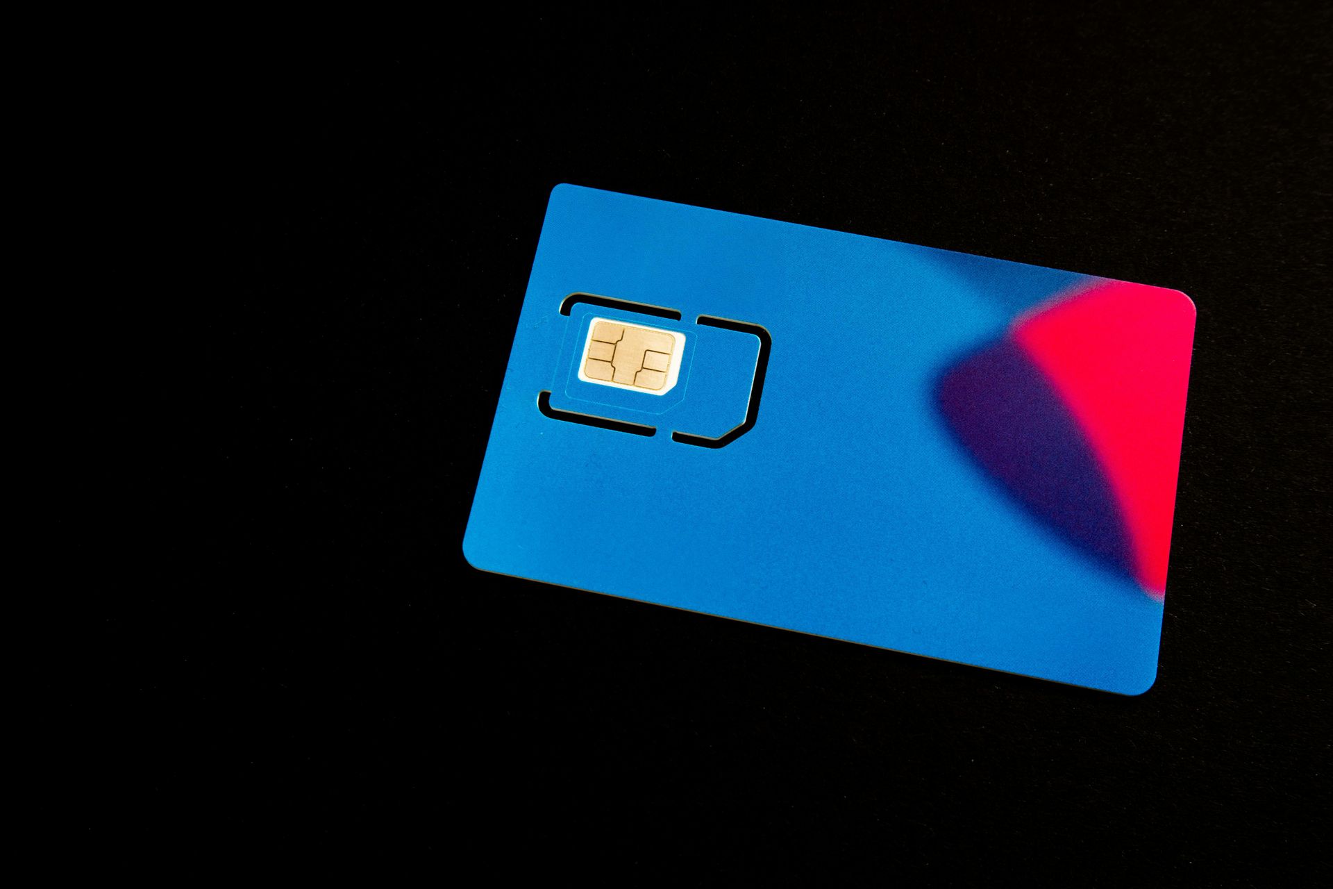 Blue SIM card with red shadow on black background.