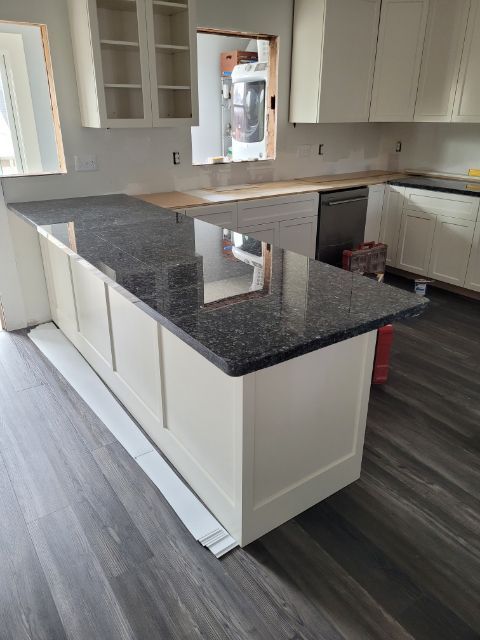 A kitchen with a black granite counter top and white cabinets.