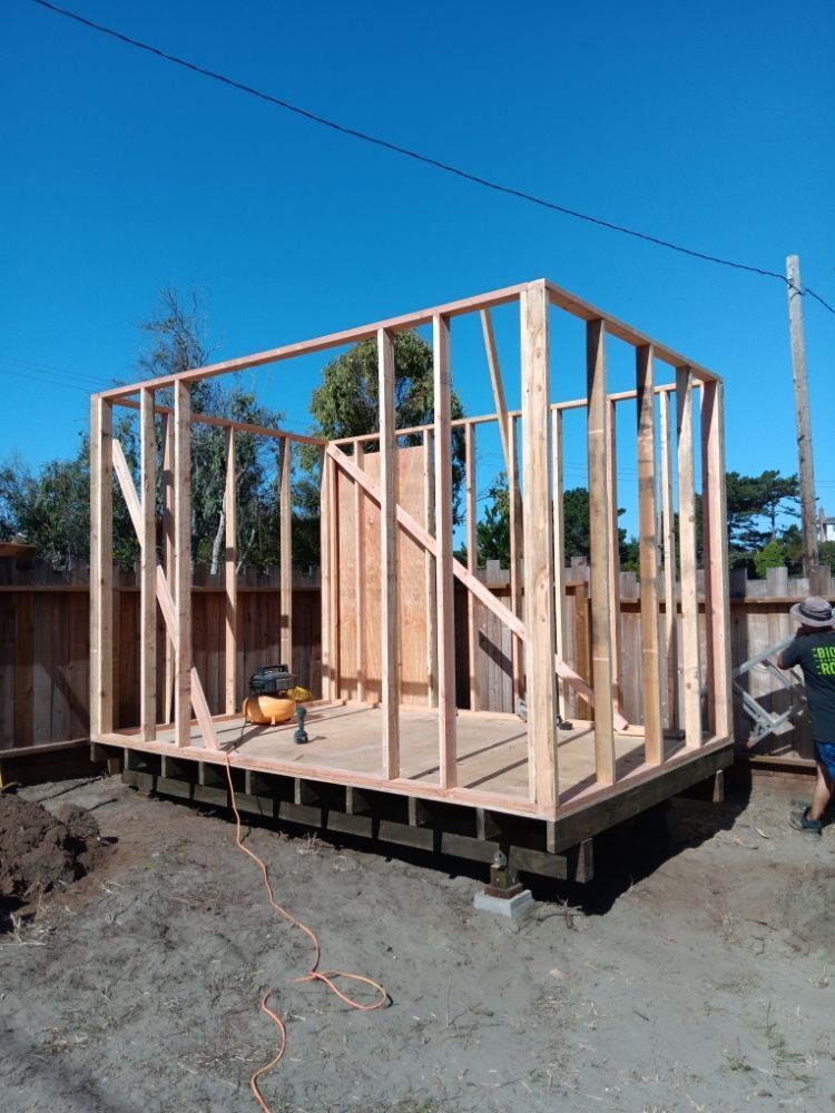 A wooden shed is being built in a backyard