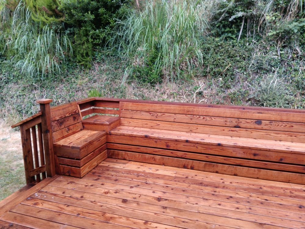 A wooden deck with a bench and a railing.
