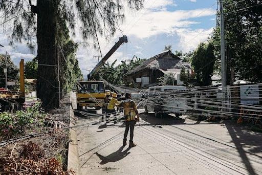 Utility workers repairing fallen power lines and storm damage on a residential street after severe w