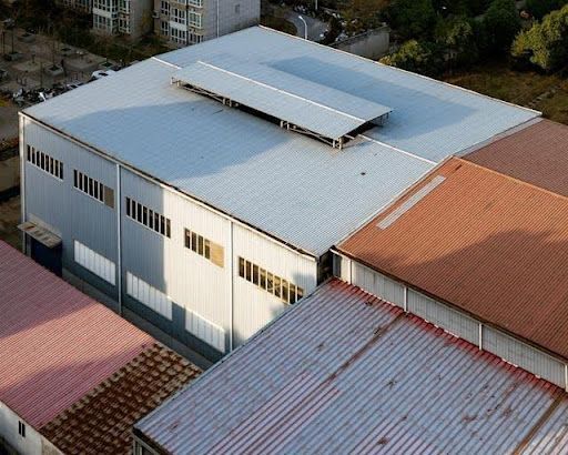 Aerial view of a large industrial warehouse with metal roofing panels and commercial building struct