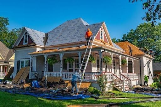 Residential roof replacement project with roofing contractors installing new shingles on a large fam
