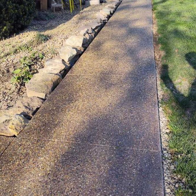 A concrete walkway with a stone wall on the side of it.