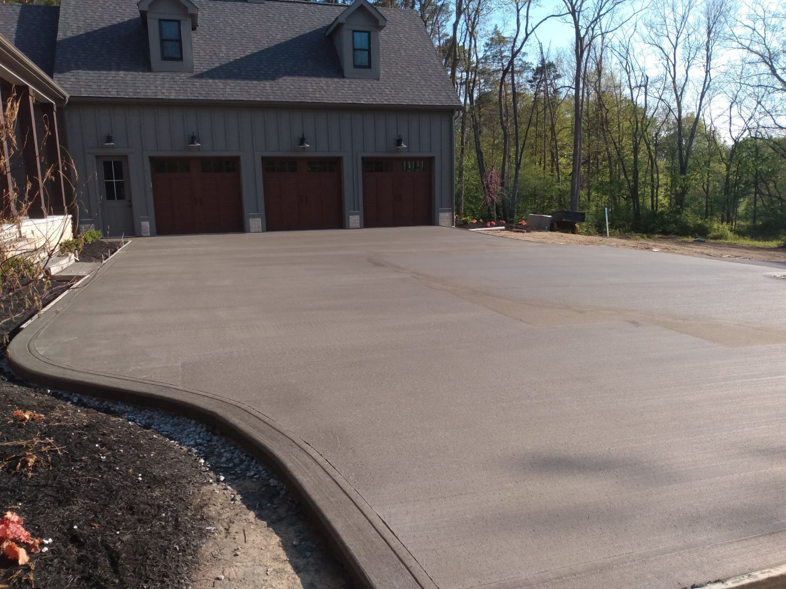 A concrete driveway leading to a house with three garage doors