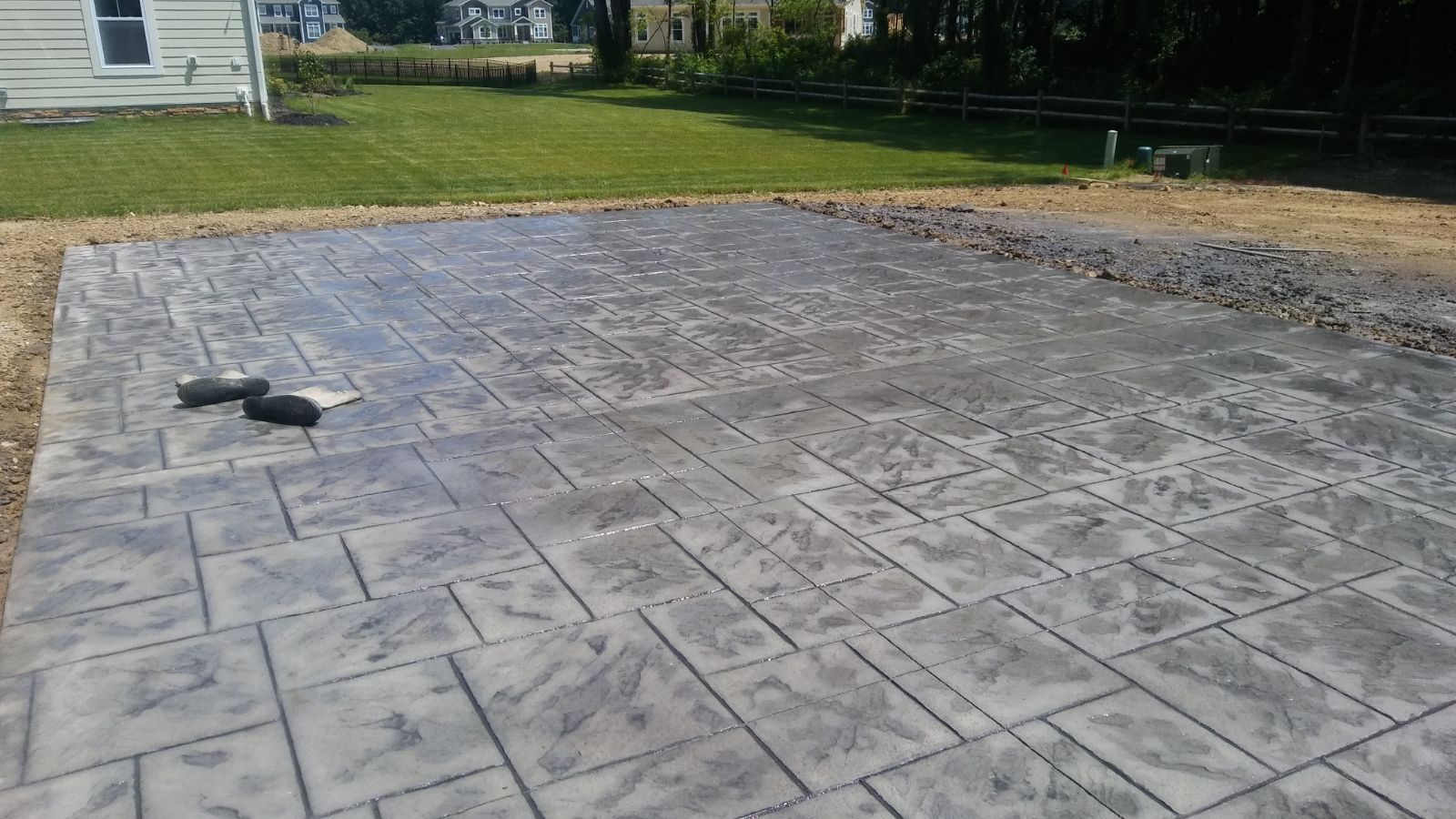 A concrete driveway in a backyard with a house in the background