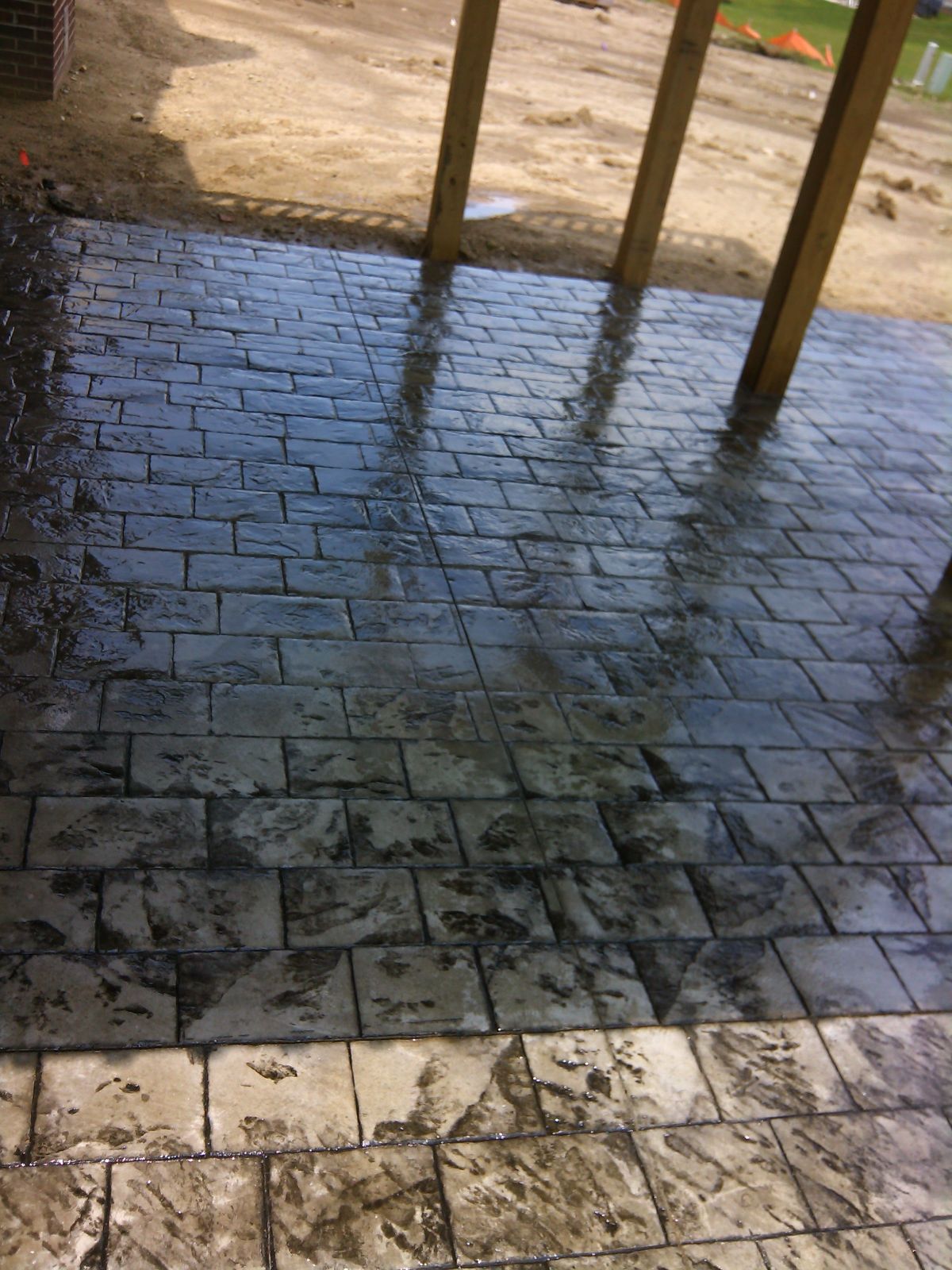 A brick walkway with a wooden structure in the background