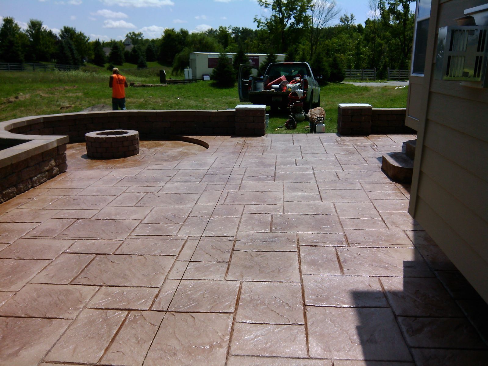A man in an orange shirt is standing on a patio