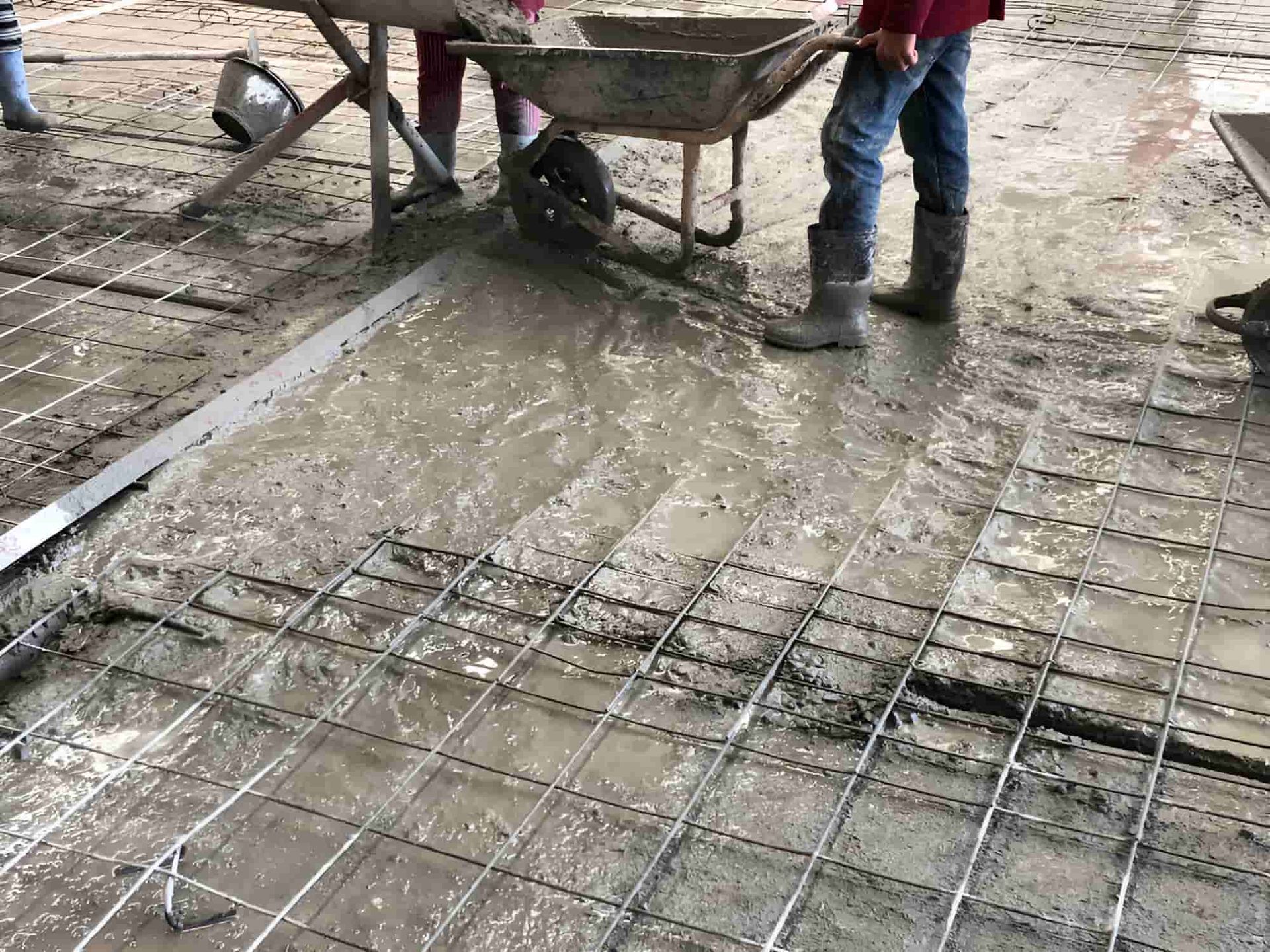 A Person Is Pouring Concrete Into A Wheelbarrow On A Construction Site — JGA Concreting Pty Ltd In Berrimah, NT