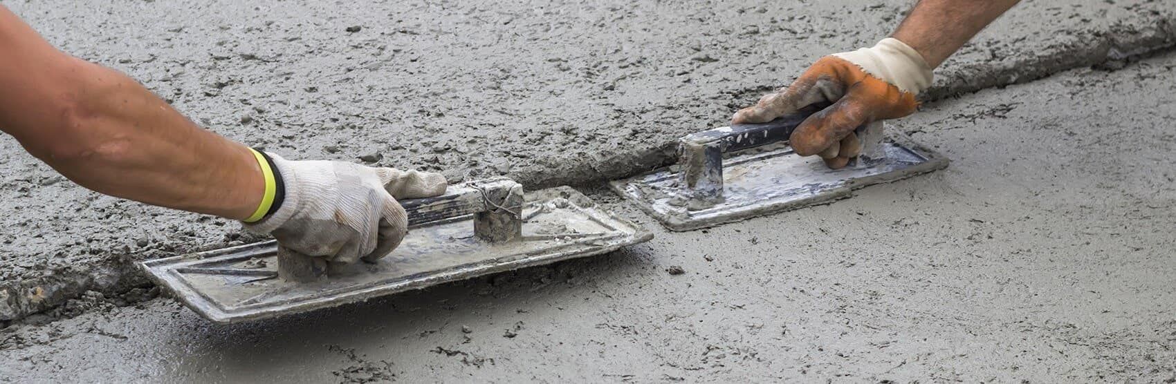 A Person Is Spreading Concrete On The Ground With A Trowel — JGA Concreting Pty Ltd In Berrimah, NT