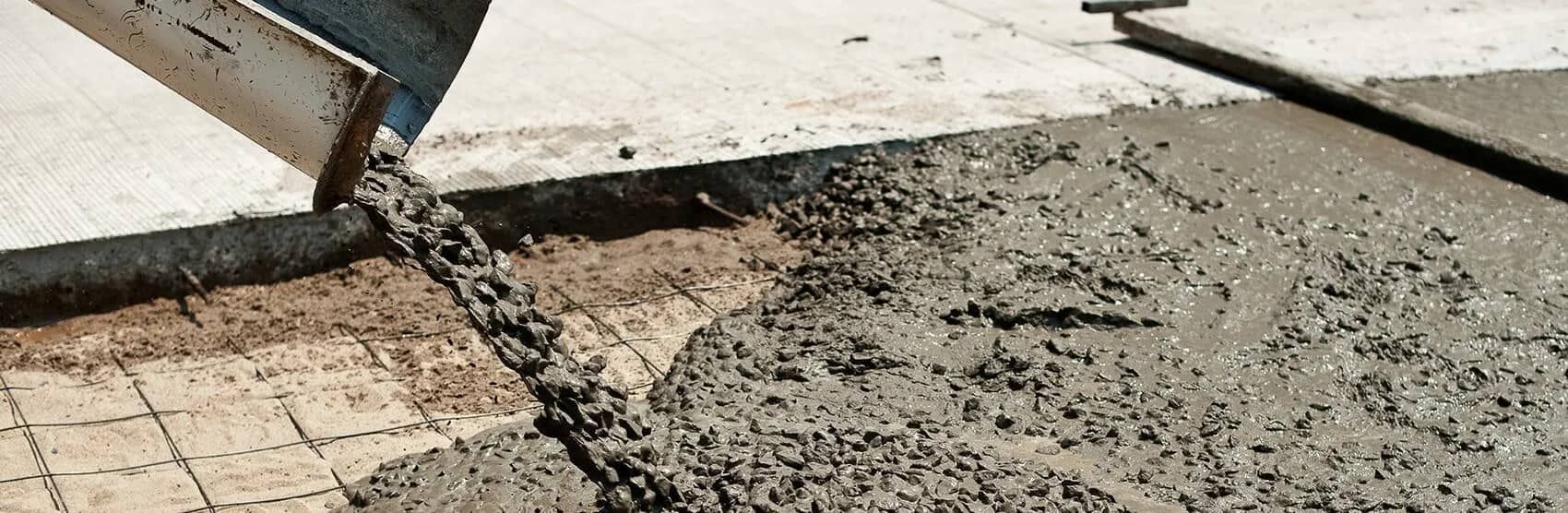 A Person Is Pouring Concrete On A Sidewalk With A Shovel — JGA Concreting Pty Ltd In Berrimah, NT