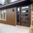 Brown house exterior with a modern front door, sidelight, and windows.