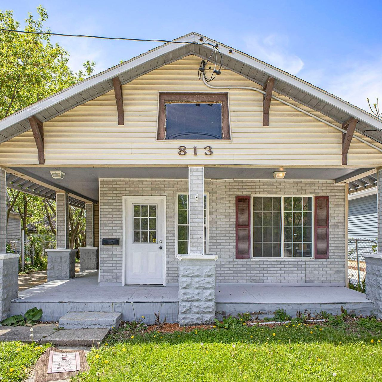 Front exterior of a single-story house with a porch and the number 813 above the door.