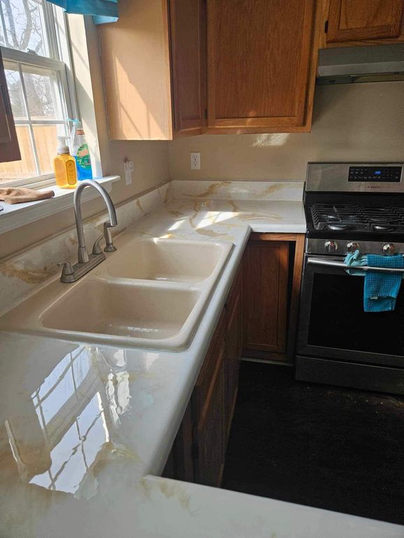 A kitchen with two sinks , a stove , and a window.