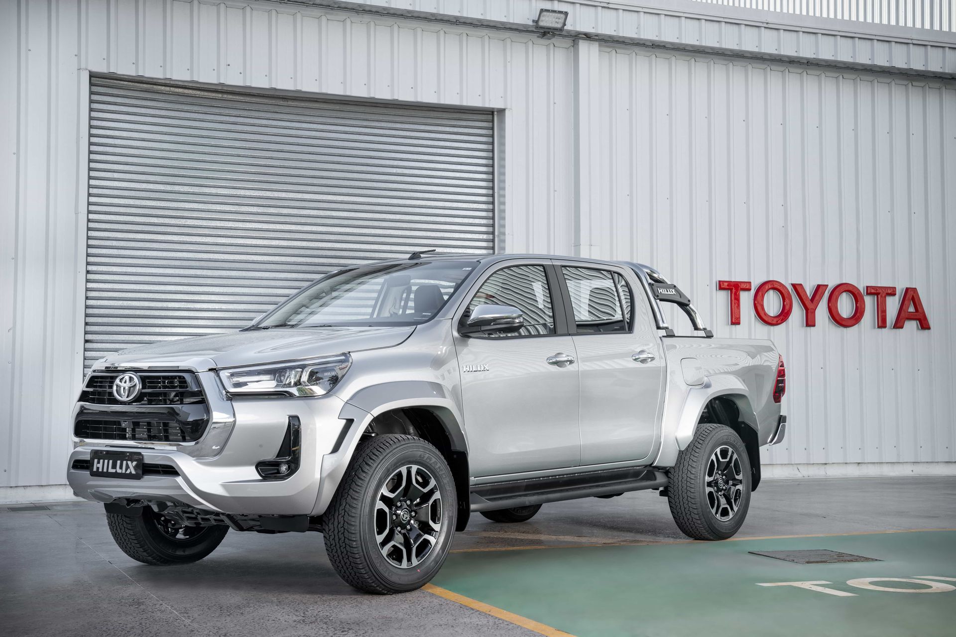 Una camioneta Toyota Hilux plateada está estacionada frente a un edificio.
