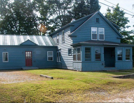 A blue house with a striped roof and a red door