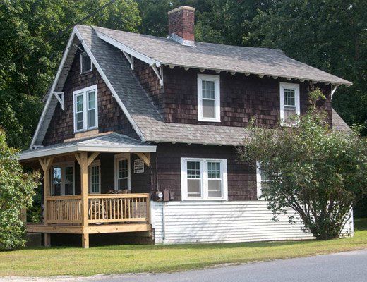 A brown and white house with a porch and a chimney