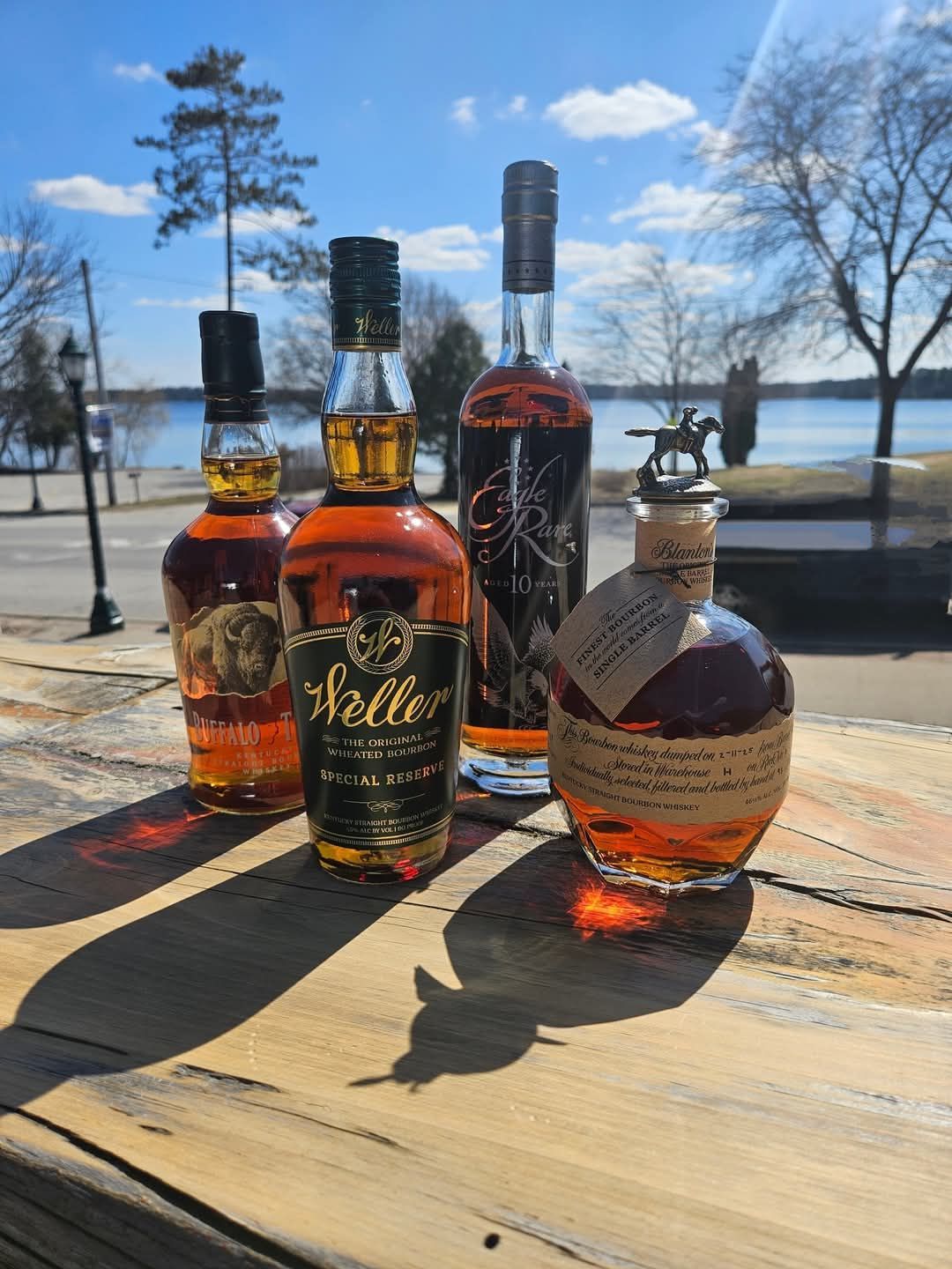 Three bottles of whiskey are sitting on a wooden table.