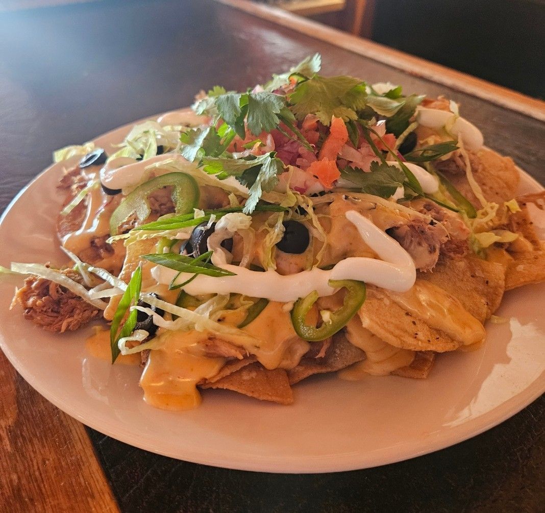 A close up of a plate of nachos on a table.