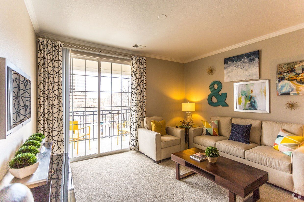 Living room with balcony access, beige couch, and art at The Viridian in Greenwood Village, CO.