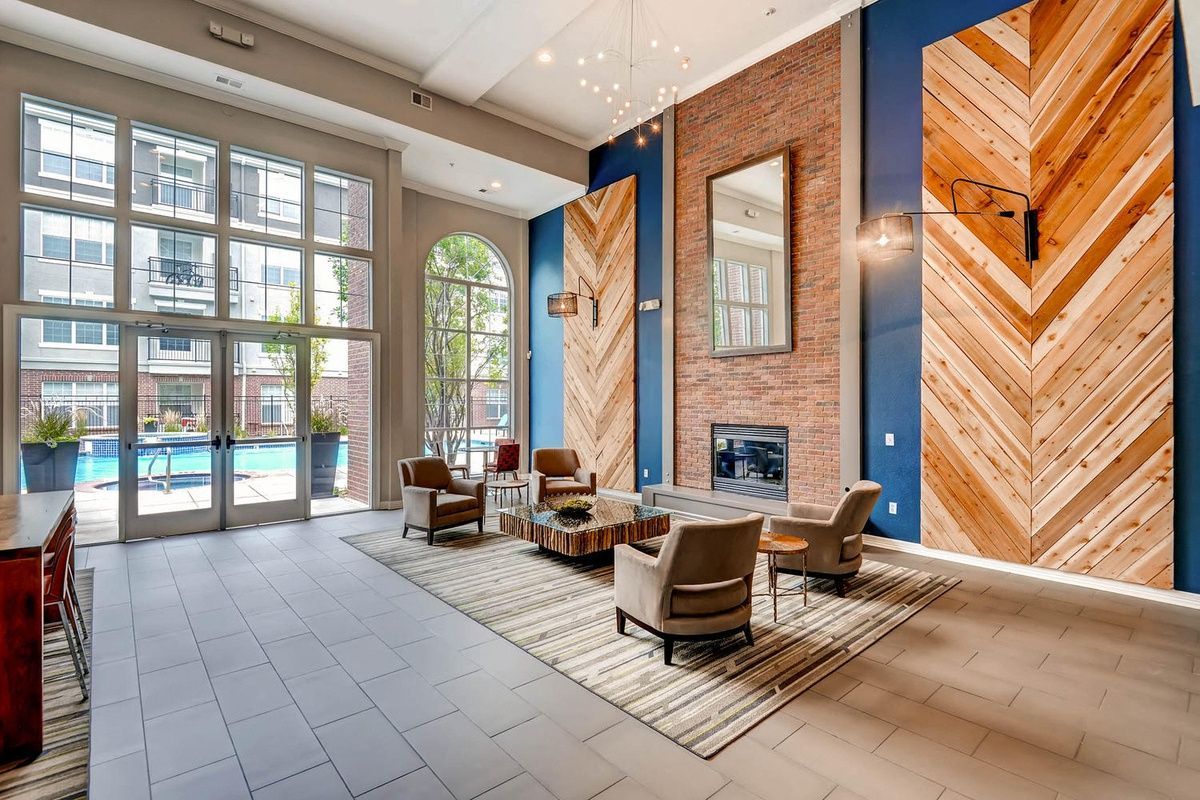 Lobby with seating area, pool view. Blue walls, brick fireplace, chevron wood panels, large windows, contemporary design at The Viridian in Greenwood Village, CO.