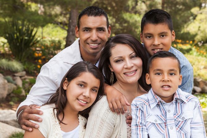 Family of five smiling together outdoors.
